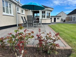 a patio with a table and chairs and an umbrella at Rose Cottage in Portadown