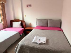 a bedroom with two beds with pink and white sheets at Hotel Manhattan City in Duitama
