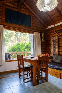 a dining room with a table and chairs and a window at Cabañas Mapuche in Mar de las Pampas
