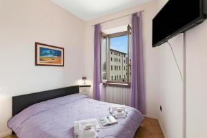 a bedroom with a bed and a window with purple curtains at Lake View Historical Center Apartment - Happy Rentals in Riva del Garda