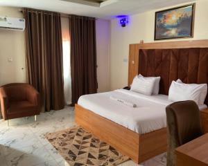 a hotel room with a bed and a chair at The Tusk Hotel in Kuje