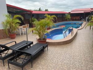 a resort pool with benches and a table and chairs at The Tusk Hotel in Kuje