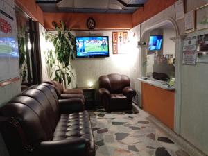 a waiting room with leather chairs and a television at Hotel Manhattan City in Duitama