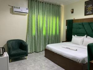 a bedroom with a bed and a green curtain and a chair at The Tusk Hotel in Kuje