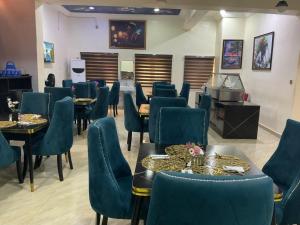 a restaurant with blue chairs and tables and a television at The Tusk Hotel in Kuje