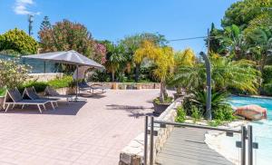 a patio with chairs and an umbrella next to a pool at Villa Joel in Fontane Bianche