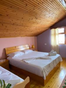 a bedroom with a large bed with a wooden ceiling at Blero Rooms Rent in Pogradec