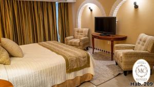 a hotel room with a bed and a tv and chairs at Mansión del Cobre Hotel Boutique in Los Mochis
