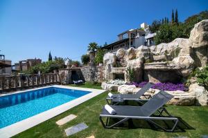 a pool with two lounge chairs next to a rock wall at Villa Stone Bodrum - Private Pool & Garden in Bodrum City