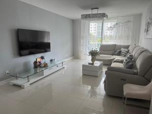 a white living room with a couch and a tv at Condominium Sunny Isles Ocean Reserve in Sunny Isles Beach