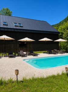 a swimming pool with chairs and umbrellas and a building at Cabana Crang in Dobra