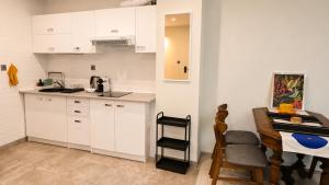 a kitchen with white cabinets and a table and a chair at Centrum Warszawy - City Center the best places, metro Centrum & Świętokrzyska, partial view of the Palace of Culture, self check-in, AC, optional breakfest in Warsaw