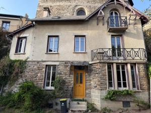 an old stone house with a yellow door at Maison Bécharie in Uzerche