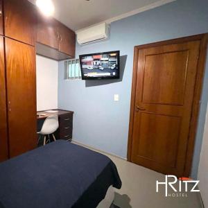 ein Schlafzimmer mit Bett, Schreibtisch und Fernseher in der Unterkunft Ritz Hostel in Araçatuba