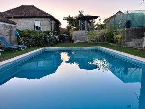 a swimming pool with blue water in front of a house at Casa da Ponte in Baião