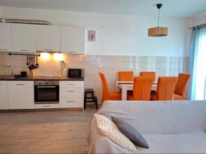 a living room with a kitchen and a table with orange chairs at Zen Olive Retreat in Petrovac na Moru