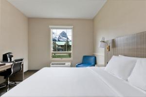 a bedroom with a bed and a desk and a window at Grande Rockies Resort-Bellstar Hotels & Resorts in Canmore