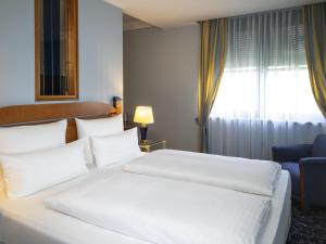 オーバーディングにあるAtomis Hotel Munich Airport by Mercureの白いベッドと窓のあるホテルの部屋