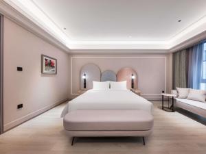 a bedroom with a large white bed and a couch at Mercure Xi'an Stadium Hotel in Xi'an +136 photos