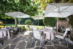 un patio avec des tables et des parasols dans un jardin dans l'établissement Landgasthof Wartegg, à Wigoltingen