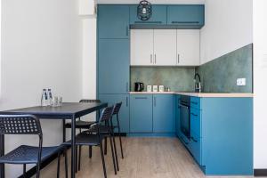 a kitchen with blue cabinets and a table with chairs at Plac Solny 4 Discreet&Comfort Głogów in Głogów +21 photos