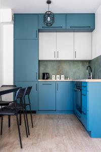 a kitchen with blue cabinets and a table and chairs at Plac Solny 4 Discreet&Comfort Głogów in Głogów