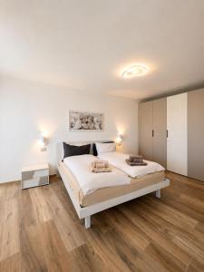 a white bedroom with a large bed and wooden floors at Casa Guerines in Tremosine Sul Garda