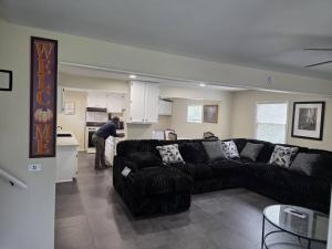 a living room with a black couch and a kitchen at Beach Vacation Home in Rochester