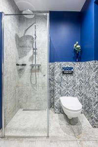 a bathroom with a shower with a toilet and a blue wall at Plac Solny 4 Discreet&Comfort Głogów in Głogów