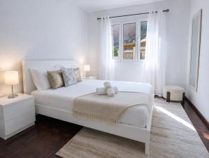a white bedroom with a white bed and a window at Villa Herédia - 5 min form the beach in Ribeira Brava