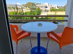 a white table and two orange chairs on a balcony at Villa Maroula in Afantou