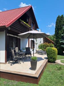a patio with an umbrella and a table and chairs at Sunshine Vendégház Balatonfenyves in Balatonfenyves