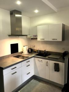 a white kitchen with white cabinets and a sink at Appartement moderne climatisé in Nyons +3 photos