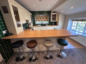 a kitchen with a large wooden island with bar stools at Eagle Cottage in Penrith +7 photos