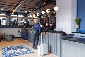 a man standing at a bar with his luggage at Holiday Inn - the niu, Quay Hamburg Harburg by IHG in Hamburg