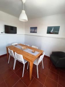 a dining room with a wooden table and white chairs at Ria de Aveiro White House in Murtosa