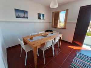 a dining room with a wooden table and white chairs at Ria de Aveiro White House in Murtosa
