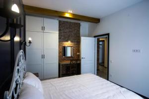 a bedroom with a white bed and a brick wall at Potocki Apartments in Lviv