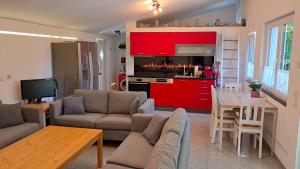 a kitchen and living room with red cabinets and a table at Das Gartenhaus - Lottstetten in Lottstetten