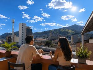 a man and woman sitting at a table on a roof at Hotel Mediterraneo Quito in Quito