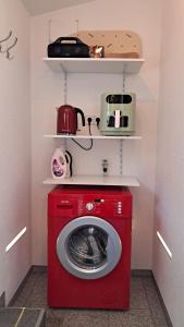 a red washing machine in a room with shelves at Das Gartenhaus - Lottstetten in Lottstetten +24 photos