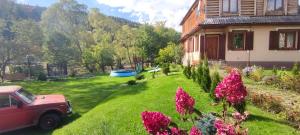 a yard with a house and a car and flowers at Arnika Tatariv in Tatariv