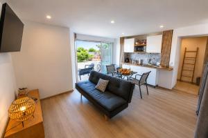 a living room with a black couch and a table at Le Refuge Marin - Vue Mer - Accès direct Plage - Terrasse - Climatisation - Place de Parking in Leucate-Plage