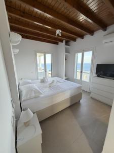a white bedroom with a bed and a television at The Aegean Horizon Villa in Grótta +86 photos