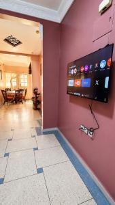 a room with a flat screen tv on a purple wall at Appt Spacieux, Confortable, Calme, et Lumineux, Proche de la Plage avc Fibre Optique in Safi