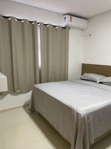 a bedroom with a bed with white sheets and a window at AL&V Hotel in Santa Tereza do Oeste