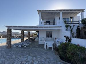 a white house with a table and chairs and a pool at The Aegean Horizon Villa in Grótta
