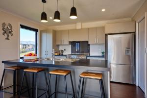 a kitchen with a large counter with stools in it at Spacious, Family-Friendly, Parkside - KK67479 in Kaikoura