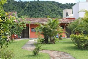 a house with a palm tree in the yard at O Melhor Chalé da Praia do Guaiúba, com Churrasqueira e Piscina Gigante in Guarujá