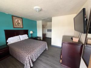 a hotel room with a bed and a flat screen tv at Encore Motel in Farmington
